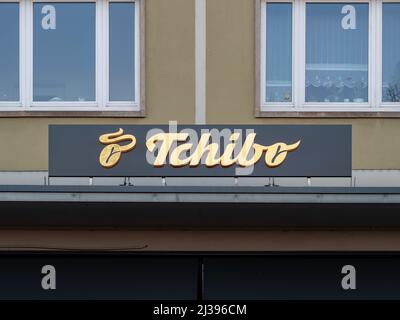 Logo del negozio Tchibo di fronte alla facciata dell'edificio. Catena di caffetterie e caffetterie. L'azienda vende anche prodotti diversi dal caffè. Servizio catering Foto Stock