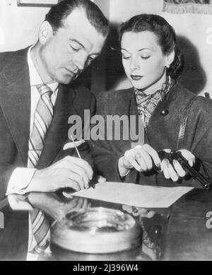 Hedy and Mate Seek Gun Permit -- l'attrice Hedy Lamarr tiene un revolver mentre suo marito, John Loder, firma una domanda per un permesso di pistola ai quartieri di testa della polizia oggi. La loro casa è stata burglarizzata l'altra notte del $18.400 in pellicce e gioielli. Film Stars Hedy Lamarr e il marito John Loder hanno recentemente firmato una domanda per un permesso revolver dopo che la loro casa era stata scampata. Hedy Lamarr tiene il revolver. Gli scassinatori hanno preso i furs, i monili e 18.400 dollari. Aprile 19, 1946. (Foto di AP Wirephoto). Foto Stock