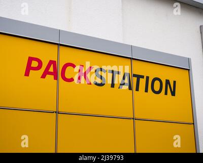 Logo DHL Packstation su un armadietto giallo accanto a un edificio. Lettere della stazione di confezionamento per ricevere pacchi da qualsiasi luogo. Foto Stock