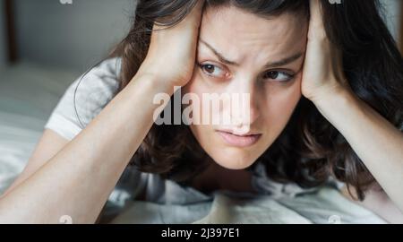 Donna triste e infelice sdraiata a letto in depressione. Mal di testa,stress,ansia,tensione,problemi psicologici. Cattiva salute mentale,psicologo in visita,psico Foto Stock