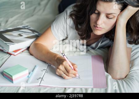 Donna, giovane ragazza scrive pagine del mattino, prende appunti nel diario personale dei pensieri, salute mentale. Stesura di piani, elenchi di attività. Lavoro remoto a casa. St Foto Stock