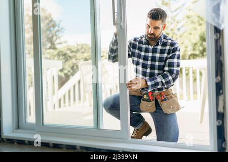 bel giovane uomo che installa la finestra di baia in un nuovo cantiere Foto Stock