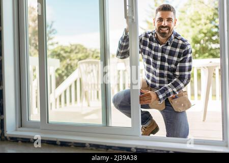 bel giovane uomo che installa la finestra di baia in un nuovo cantiere Foto Stock