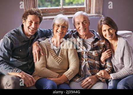 All'interno del diritto. Un ritratto di genitori maturi felici seduti con i loro figli adulti a casa. Foto Stock