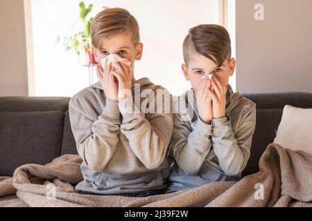 tosse i ragazzi dei piccoli fratelli a casa che hanno influenza sul divano Foto Stock