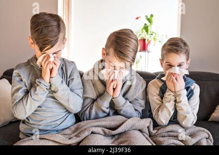 tosse i ragazzi dei piccoli fratelli a casa che hanno influenza sul divano Foto Stock