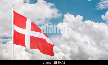 Bandiera danese su flagpole contro cielo nuvoloso. Copiare lo spazio sul cielo Foto Stock