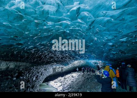 JOKULSARLON,ISLANDA - NOVEMBRE 18 2021: I turisti esplorano l'interno di una spettacolare grotta di ghiaccio sotto il ghiacciaio Vatnajökull nell'Islanda meridionale Foto Stock
