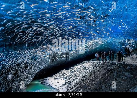 JOKULSARLON,ISLANDA - NOVEMBRE 18 2021: I turisti esplorano l'interno di una spettacolare grotta di ghiaccio sotto il ghiacciaio Vatnajökull nell'Islanda meridionale Foto Stock