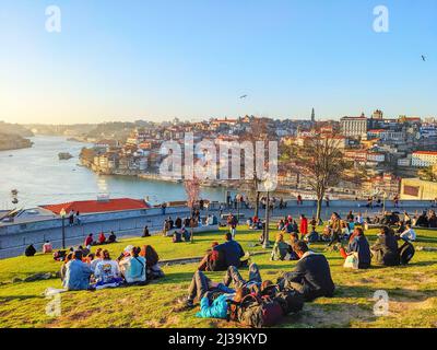 PORTO, PORTOGALLO - 21 FEBBRAIO, 2022: Persone sedute sul prato verde, Ribeira vista, Porto paesaggio urbano alla luce del sole con il fiume Douro Foto Stock