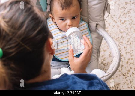 Madre che dà al bambino un biberon di latte. Foto Stock