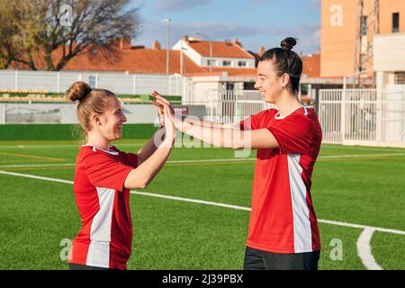 Due donne calciatrici alte-cinque l'un l'altro durante una partita di calcio Foto Stock