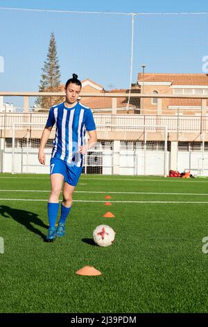Un giocatore di calcio femminile si sta allenando in un campo di calcio Foto Stock
