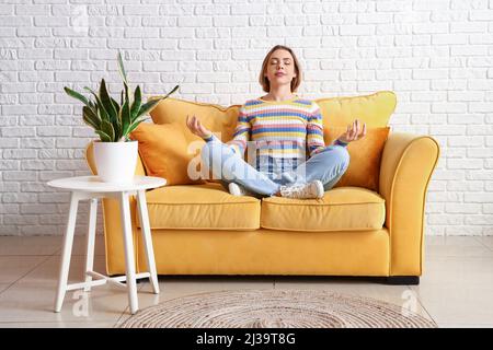 Bella giovane donna meditating sul divano a casa Foto Stock