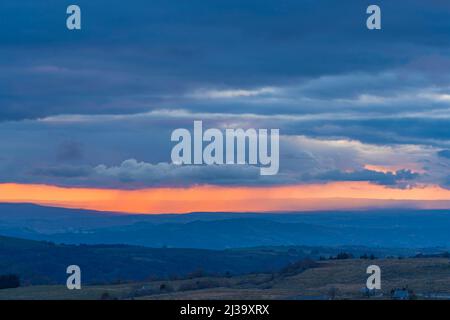 Pioggia colorata attraverso le nuvole durante il tramonto su Hills Stormy Sky Foto Stock