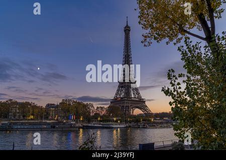 Cielo viola a Parigi al tramonto sul tramonto sulla Torre Eiffel con luna e alberi Foto Stock