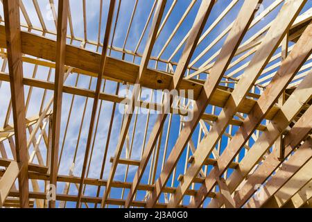 Capriate tetto in legno la nuova casa su un cielo chiaro sfondo vista in cantiere Foto Stock