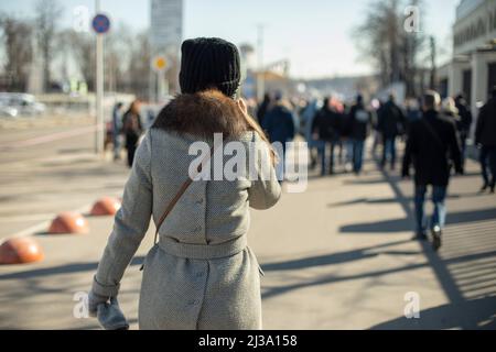 Ragazza cammina attraverso la città. Donna per strada. Abiti primaverili a persona. Camminando lungo la strada. Molta gente. Foto Stock