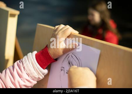 Artista dipinge su strada. La mano tiene la matita. Belle arti . Le mani della donna e malbert. Disegno verticale. Foto Stock