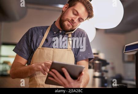 Assicurati che la tua presenza online sia tutta ciò che può essere. Scatto di un giovane che usa un tablet digitale mentre lavora in un bar. Foto Stock