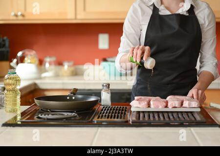 Lo chef prepara bistecche di maiale fresche in cucina, salate la carne del menu, cucinate in casa. Ricette culinarie. Menu ristorante. Foto Stock