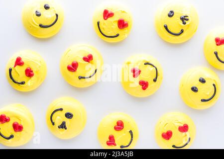 Vista dall'alto in basso di diversi biscotti merengue emoji sorridenti. Foto Stock