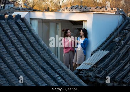 Le giovani donne cinesi si rilassano sul tetto di una tradizionale casa cortile a Pechino - foto di scorta Foto Stock