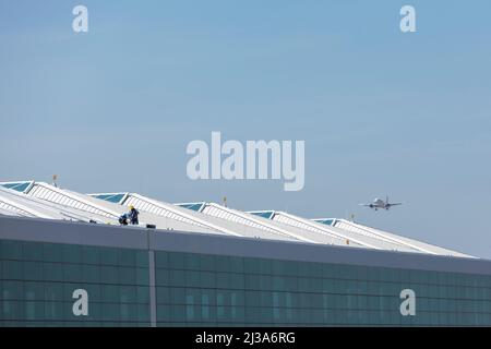 Aspetto dell'Aeroporto Internazionale di Felipe Angeles. Lavoratori sul tetto mentre un aereo atterra dentro. Foto Stock