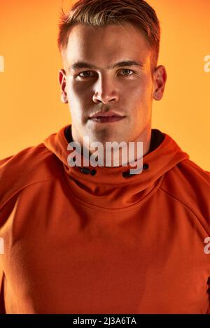 Vivere uno stile di vita sano mi rende sicuro. Ritratto da studio di un bel giovane atleta maschile che si posa su uno sfondo arancione. Foto Stock