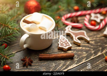 Inverno caldo dolce bere latte caldo con marshmallows e cacao in una tazza con una cannella vacanza di Natale su uno sfondo di legno, fuoco selettivo Foto Stock