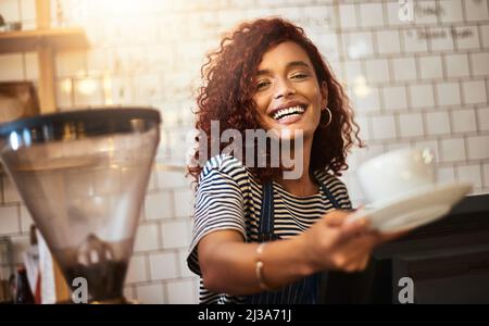 Divergetevi. Ritratto di un giovane barista che tiene una tazza di caffè in un caffè. Foto Stock
