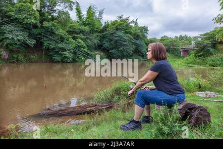 Donna pesca sul fiume Tebicuary in Paraguay. Foto Stock