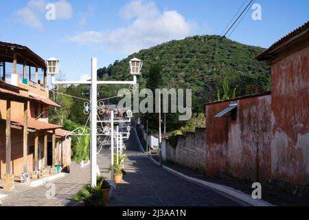 Città di Ataco a Ruta de las Flores, El Salvador. Strada vuota con marciapiede ed edifici. Vista delle colline piantagione di caffè in lontananza Foto Stock