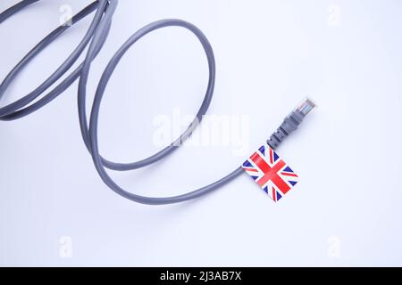 Cavo Internet con bandiera britannica. Connessione di un PC a Internet in Gran Bretagna. Primo piano del cavo multicore su sfondo bianco. Foto Stock