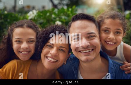 Il tempo della famiglia rende ogni faccia un volto felice. Ritratto corto di una famiglia felice che passa un po 'di tempo insieme al parco. Foto Stock