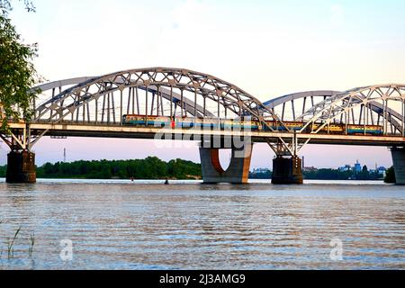 Ponte ferroviario attraverso il fiume con un treno passeggeri che lo attraversa Foto Stock