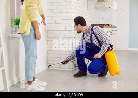 Il lavoratore di controllo di peste maschile disinfetta e spruzza appartamento con scarafaggi e roditori. Foto Stock