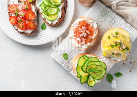 Sandwich con feta, verdure e frutta su sfondo grigio. Vista dall'alto, spazio di copia. Foto Stock