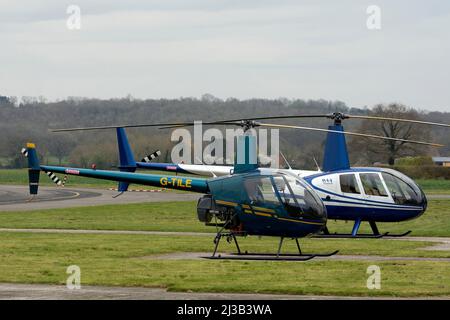 Elicotteri Robinson R22 Beta (G-TILE) e Robinson R44 Raven II (G-ORBK) presso Wellesbourne Airfield, Warwickshire, Regno Unito Foto Stock