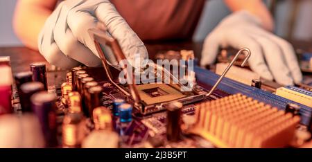 Il guanto del tecnico tiene il chip della CPU sullo sfondo della scheda madre. Concetto di microelettronica hardware ad alta tecnologia Foto Stock