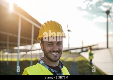 Persone che lavorano per pannelli solari e turbine eoliche - concetto di energia rinnovabile - Focus sul volto dell'uomo Foto Stock