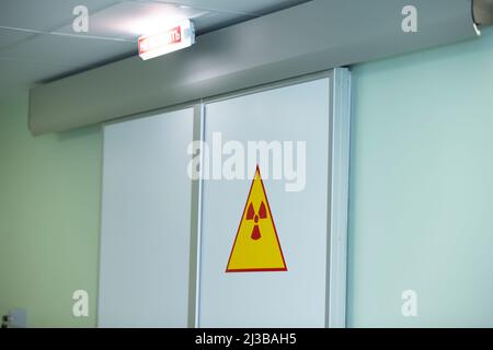 Segnale di radiazione sulle porte dell'ospedale. Avvertenza radiazioni elevate. Foto Stock