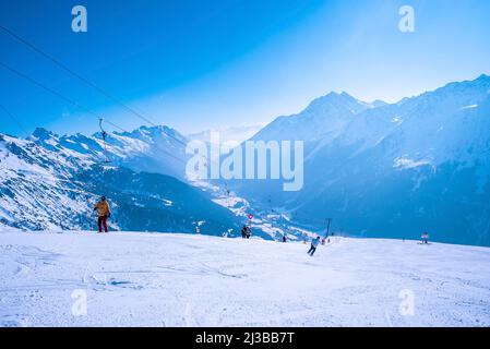 Gli sciatori che camminano sulle piste di montagna innevate nella località invernale nelle giornate di sole Foto Stock