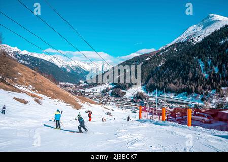 Sciatori che scivolano lungo la pista innevata in montagna nella località invernale Foto Stock