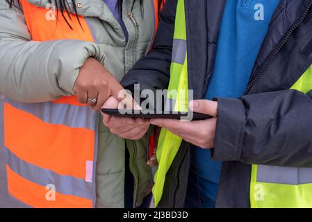 Il tecnico strutturale e il personale addetto al cantiere con touch pad discutono e pianificano il lavoro per il cantiere edile all'aperto. Foto Stock