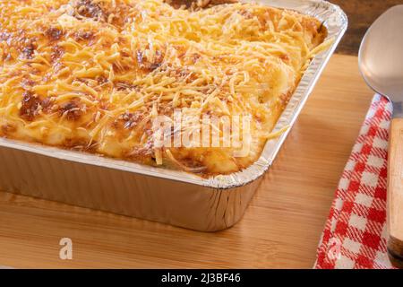 primo piano di un piatto di lasagna su un asse di legno Foto Stock