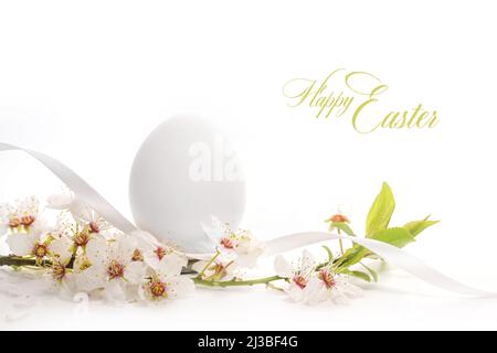 Uovo bianco con un ramo di fiori selvatici e testo buona Pasqua su uno sfondo chiaro, biglietto di auguri vacanza, spazio copia, fuoco selezionato, profondità stretta Foto Stock