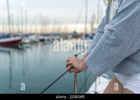 Donna croppata tenuta mano barca ringhiera in yacht marina Foto Stock