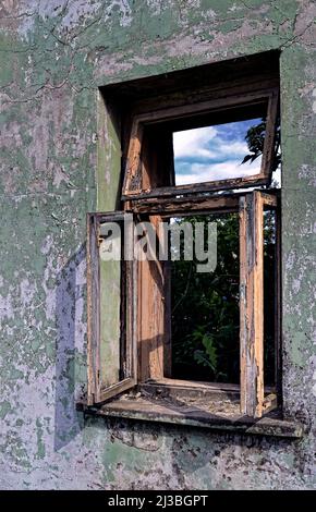 Vecchia finestra rotta con telaio in legno bianco decorativo antico dilapidato montato sulla parete della casa di famiglia incrinata. Foto Stock