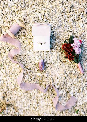 Dettagli del matrimonio viola. Spilla Ametista. Boutonniere dello sposo in tonalità bordeaux e lilla. Anello in oro con zaffiro. Disposizione piatta, vista dall'alto Foto Stock